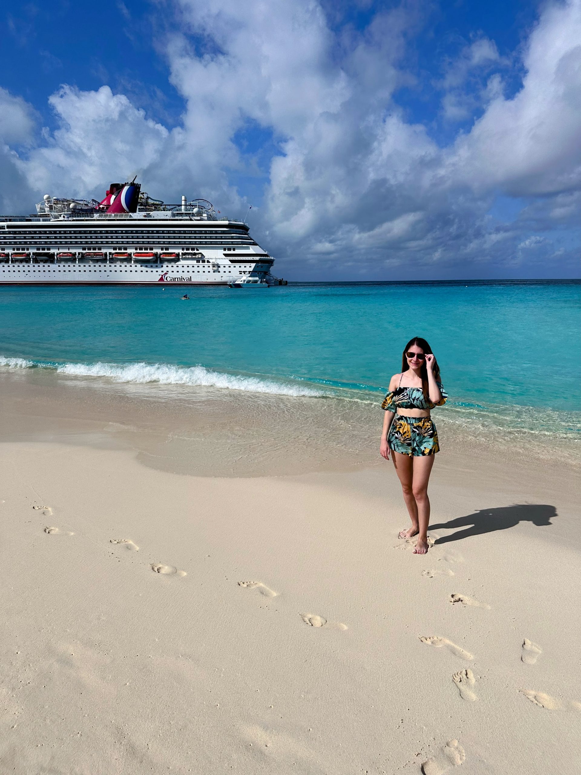 Julia standing on SunRay Beach at the Grand Turk cruise port in front of the cruise ship. 