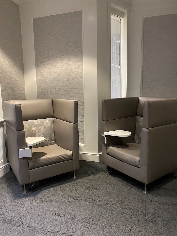 Two lounge chairs with built-in desks in the Delta Sky Club in Orlando 